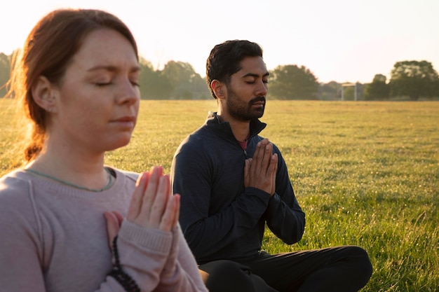 Side view of man and woman meditating outdoors