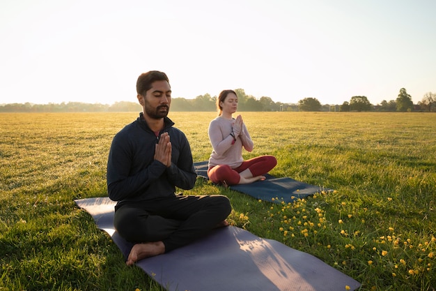 Side view of man and woman meditating outdoors