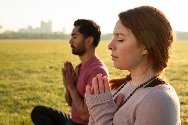 Side view of man and woman meditating outdoors