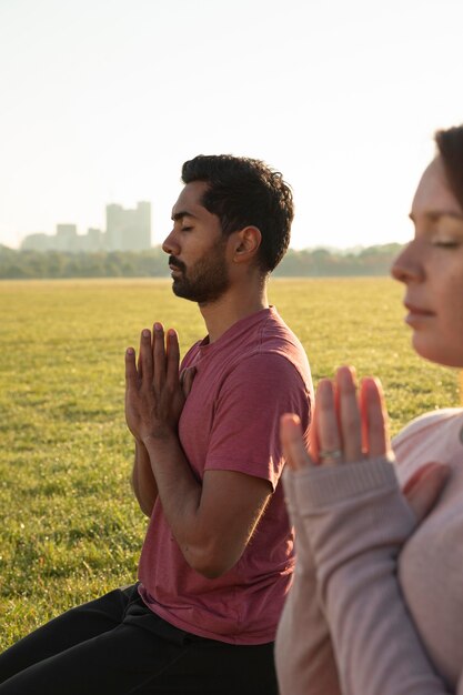 Side view of man and woman meditating outdoors