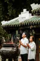 Free photo side view of man and woman praying at the temple with burning incense