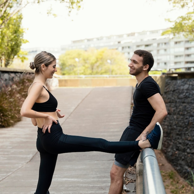 Vista laterale dell'uomo e della donna che allunga prima di esercitare all'aperto