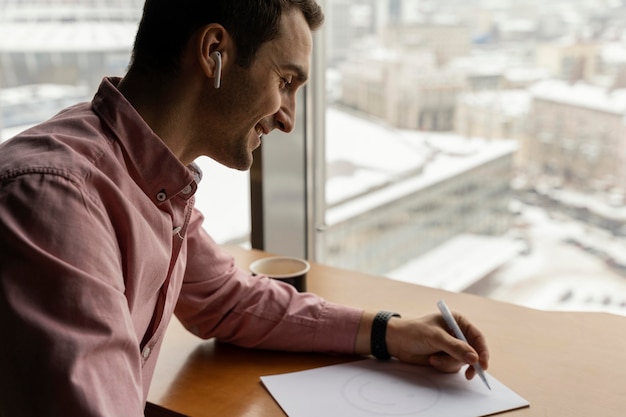 Free photo side view of man at work with earphones and documents