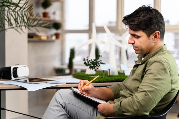 Side view of man working on an eco-friendly wind power project with clipboard