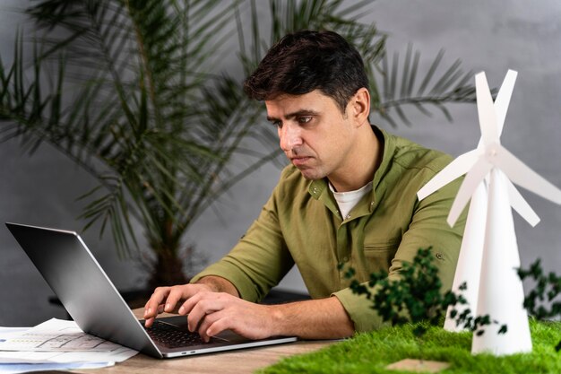 Side view of man working on an eco-friendly wind power project with laptop