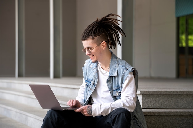 Вид сбоку мужчина работает на ноутбуке на открытом воздухе