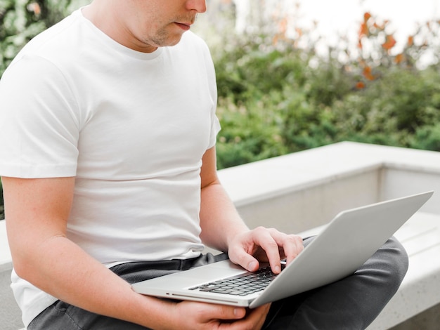Вид сбоку человека, работающего на ноутбуке снаружи