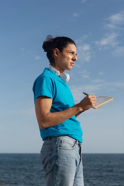 Free photo side view man writing in notebook