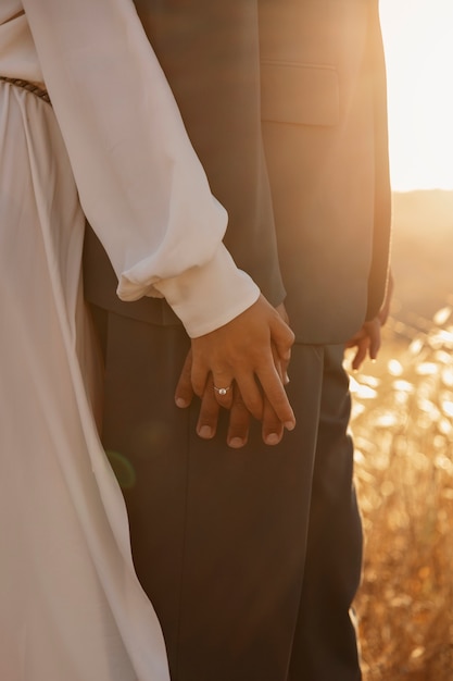 Free photo side view married couple holding hands