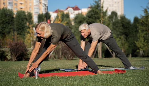 Side view of mature couple practicing yoga outdoors