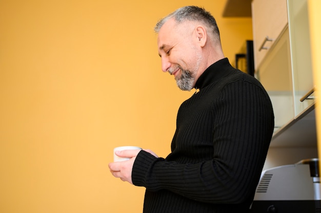 Free photo side view mature man holding a cup of coffee