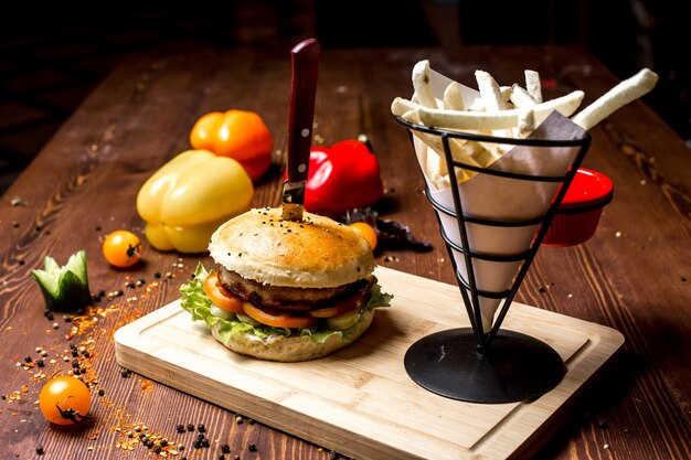 Side view meat burger with french fries on a board and bell pepper