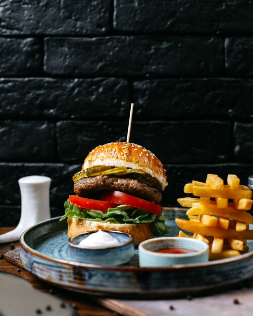 Side view meat burger with french fries ketchup and mayonnaise on tray