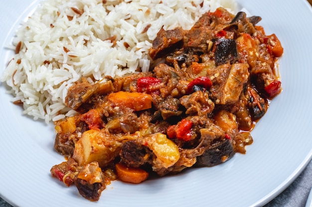 Side view meat stew lamb stew with fried onion and dried fruits with rice on a plate