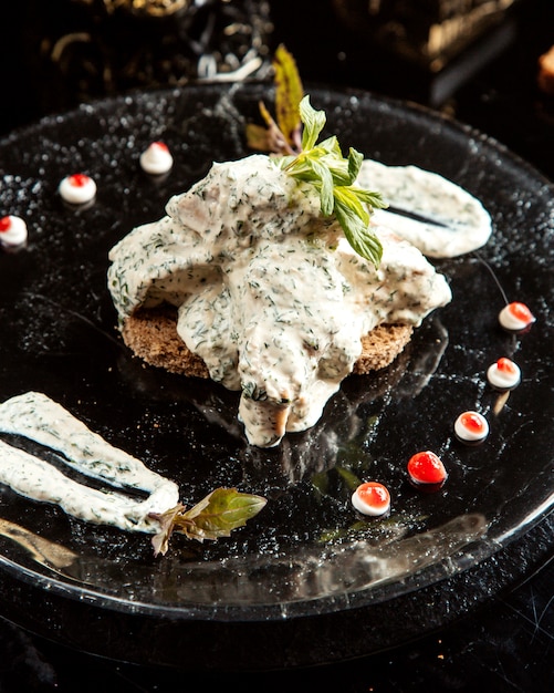 Side view of meat with greek yogurt sauce on a plate