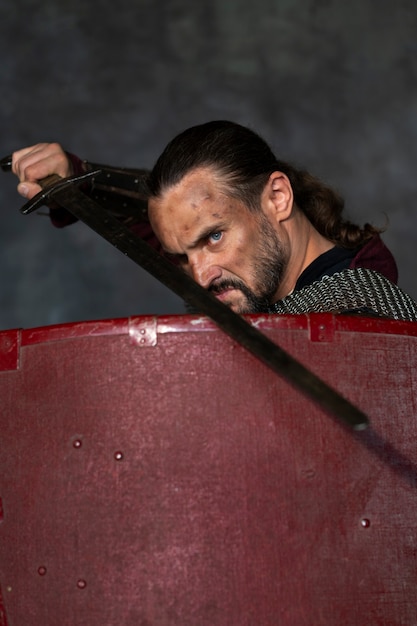 Free photo side view medieval soldier posing in studio