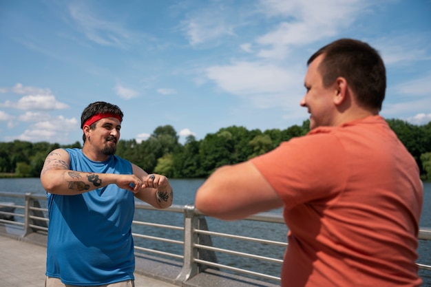 Free photo side view men exercising together outdoors