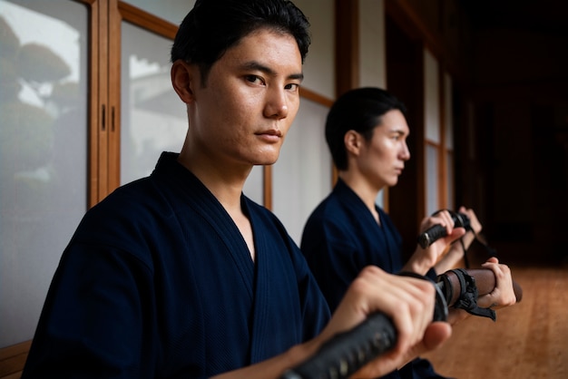 Free photo side view men in kimono holding swords