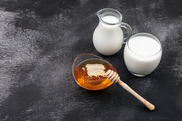 Side view of milk with honey and copy space on black surface horizontal