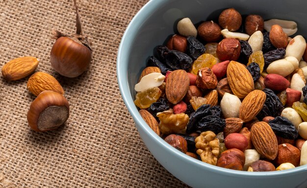 Side view of mix of nuts and dried fruits in a bowl on rustic