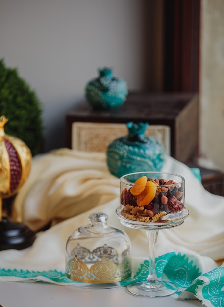 Free photo side view of mix of nuts and dry fruits in a glass vase on the tableoriental