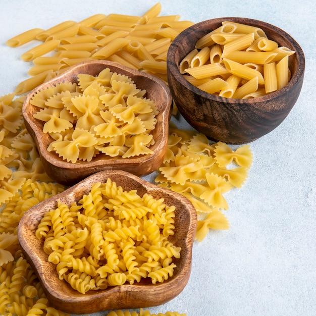 Side view of mix raw pasta in bowls on a gray surface