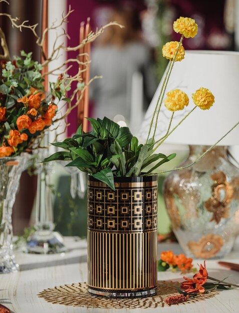 木製のテーブルに黄色い花を持つ幾何学的なパッテンとモダンなガラス花瓶の側面図