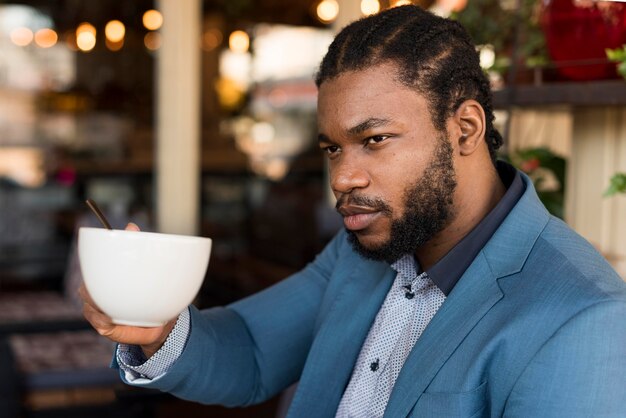 Foto gratuita uomo moderno di vista laterale che beve il suo caffè in un ristorante
