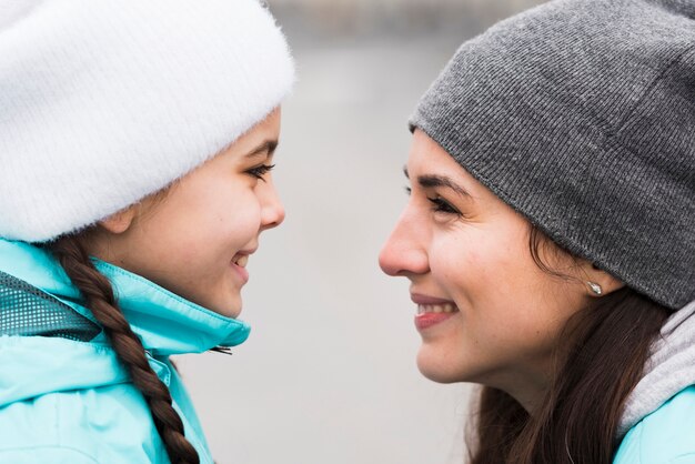 Side view mom and daughter looking at each other