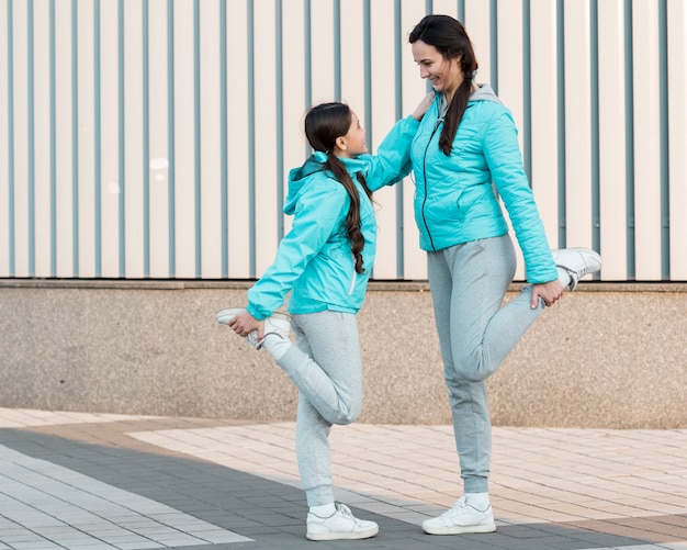 Free photo side view mom and daughter stretching