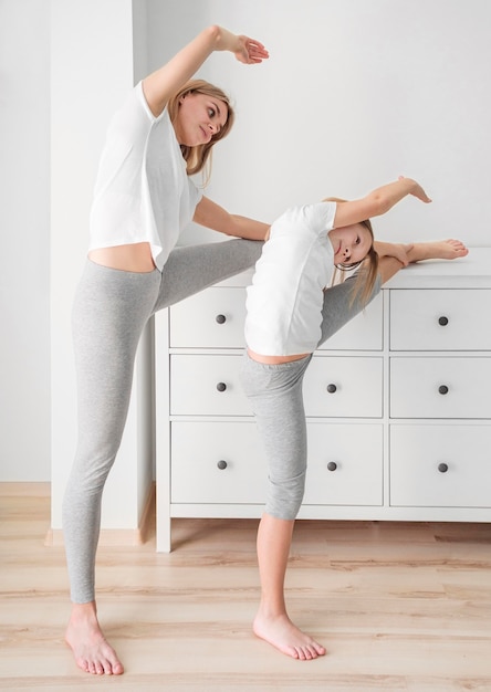 Free photo side view mom and girl stretching