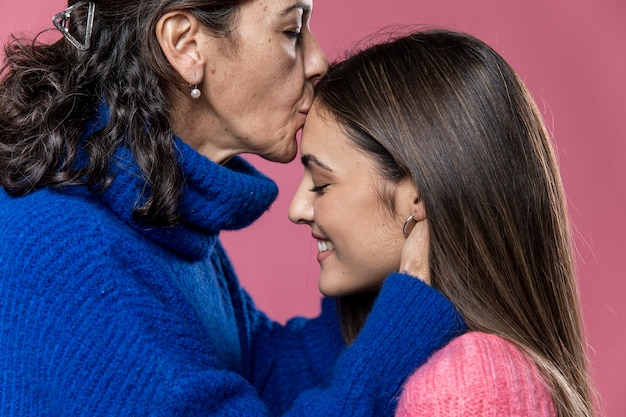 Free photo side view mom kissing daughter