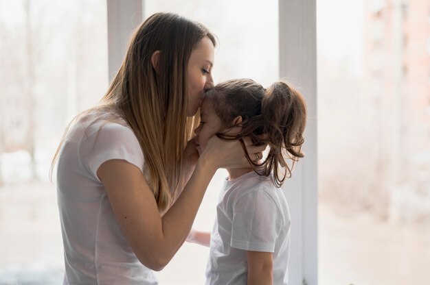 横から見たママのキスの女の子 無料の写真
