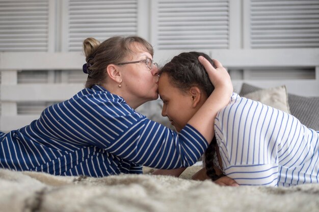 Вид сбоку мама целует девочку