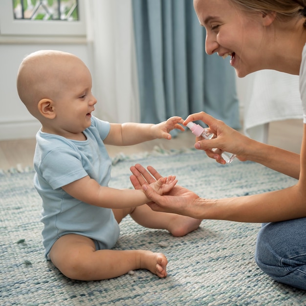 Free photo side view of mom spraying hand sanitizer on child's hands