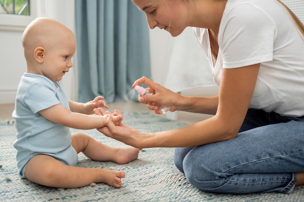 子供の手に手指消毒剤をスプレーするお母さんの側面図