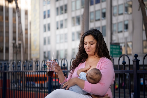 Free photo side view mother breastfeeding in public