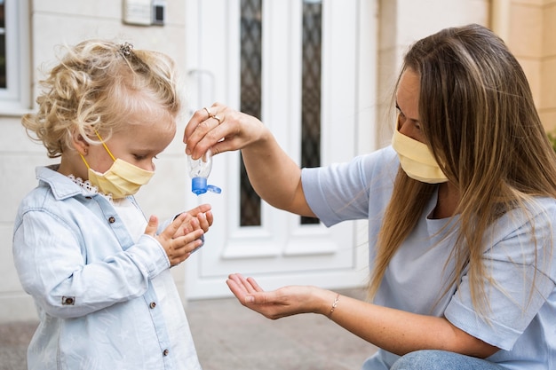 Side view of mother and child with medical masks and hand sanitizer