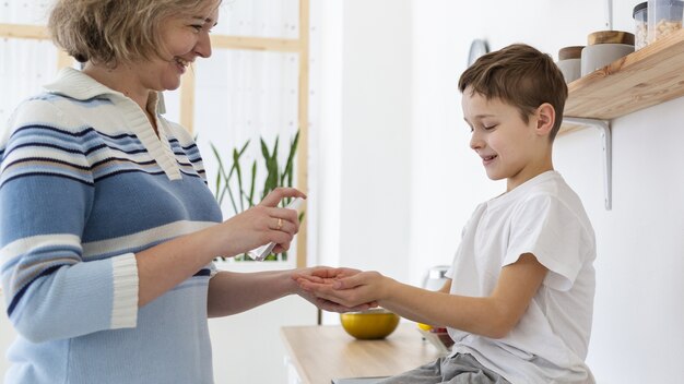 息子に手指消毒剤を与える母親の側面図