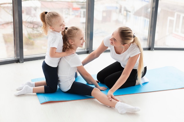 Side view of mother helping daughters exercise at home
