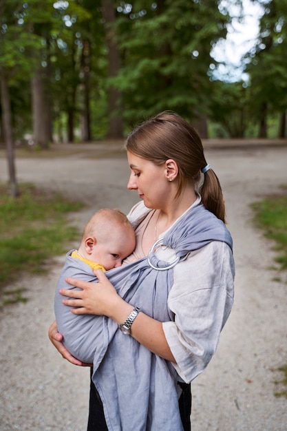 Side view mother holding baby outdoors