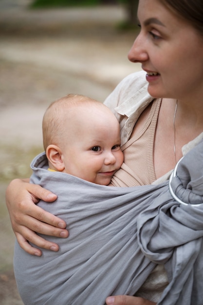 屋外で赤ちゃんを抱いている側面図の母親
