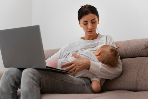 Side view mother holding baby and working