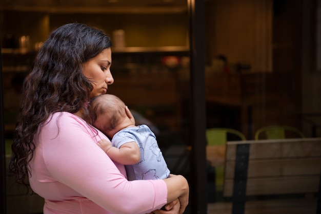 Free photo side view mother holding baby