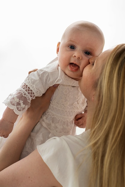 Free photo side view mother kissing baby on cheek