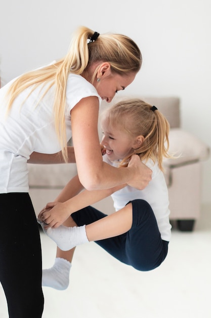 Side view of mother lifting daughter while exercising at home