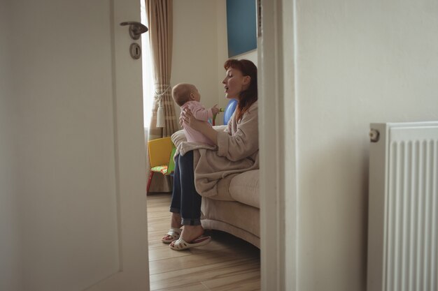 Side view of mother with baby sitting on bed