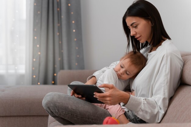 Боковой вид матери с планшетом и ребенком
