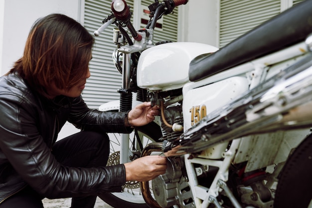 Side view of motorbiker inspecting his bike before a ride