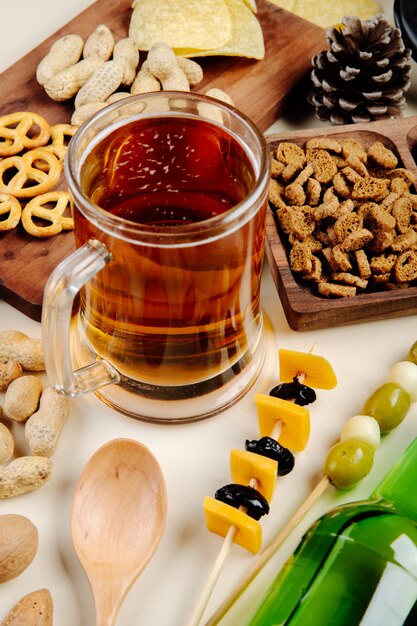 Side view of a mug of beer with various salty snacks on the table